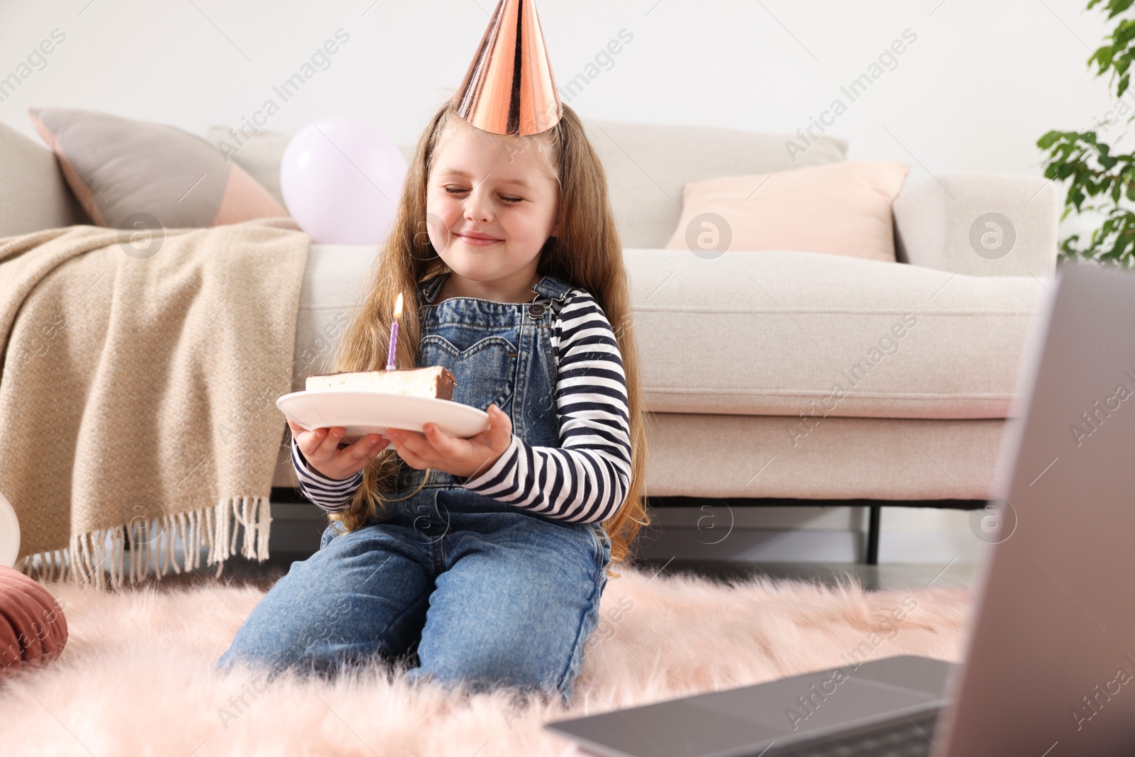 Birthday celebration. Little girl with piece of cake having video call via laptop at home Photo of Birthday celebration. Little girl with piece of cake having video call via laptop at home