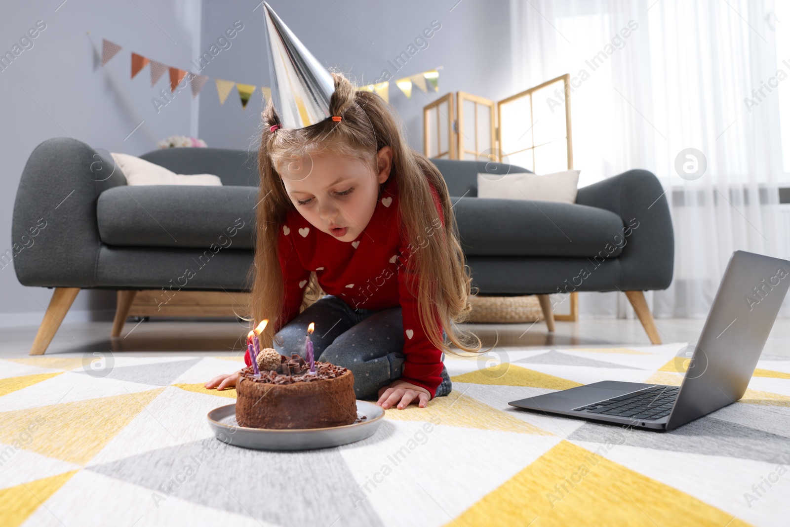 Birthday celebration. Little girl blowing candles on cake while having video call via laptop at home Photo of Birthday celebration. Little girl blowing candles on cake while having video call via laptop at home