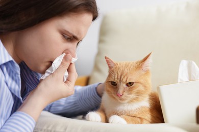 Photo of Woman suffering from allergy with her cat at home, closeup