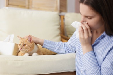 Photo of Woman suffering from allergy with her cat at home