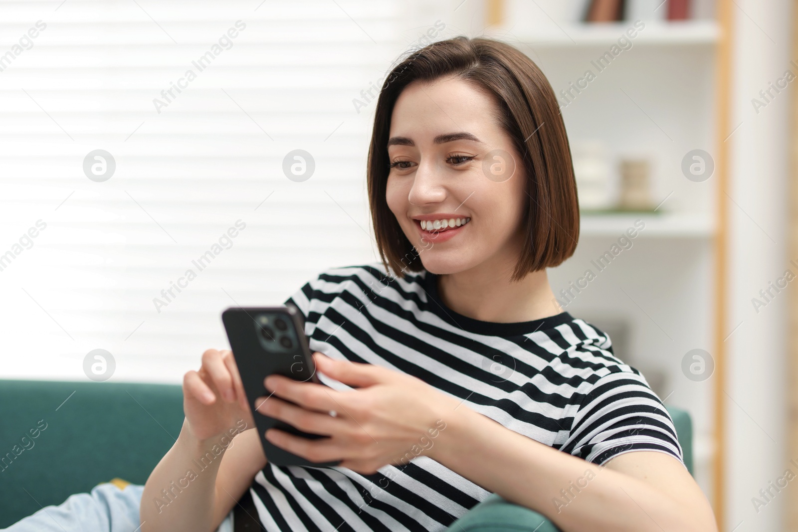 Woman using modern smartphone on sofa at home Photo of Woman using modern smartphone on sofa at home