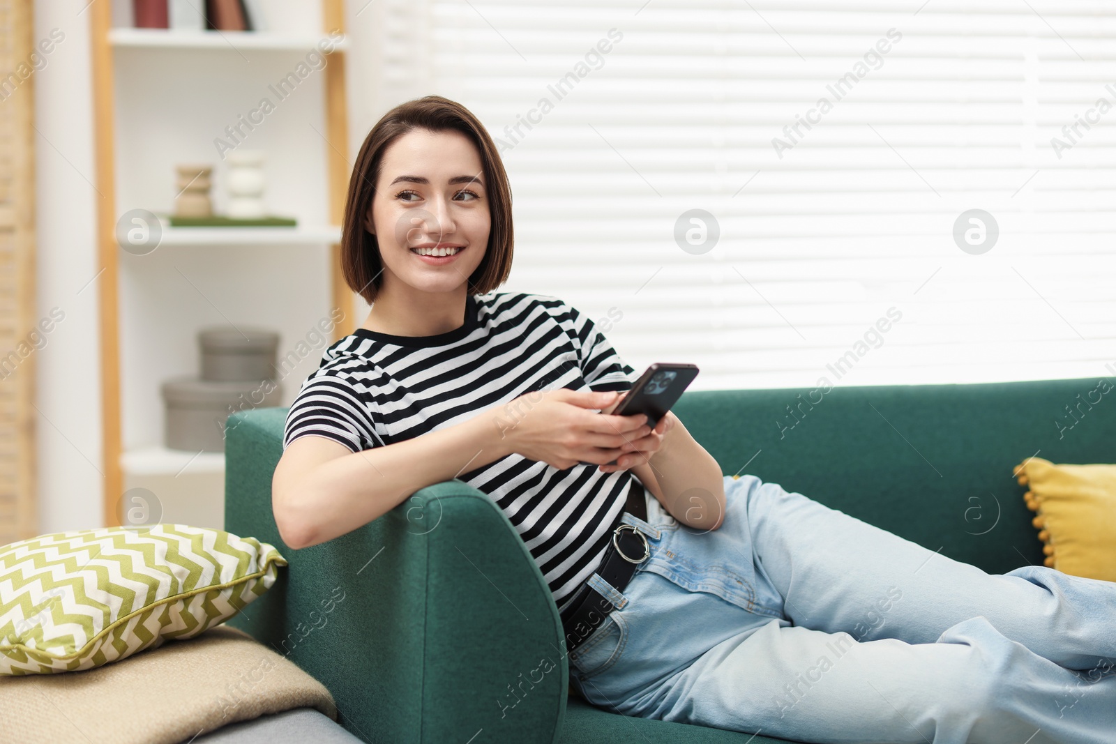 Woman using modern smartphone on sofa at home. Space for text Photo of Woman using modern smartphone on sofa at home. Space for text