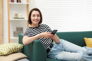 Photo of Woman using modern smartphone on sofa at home. Space for text