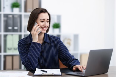 Photo of Beautiful woman talking on phone at desk in office. Space for text