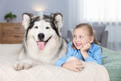 Photo of Little girl and cute dog on bed at home