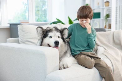 Photo of Boy suffering from allergy with her dog on sofa at home