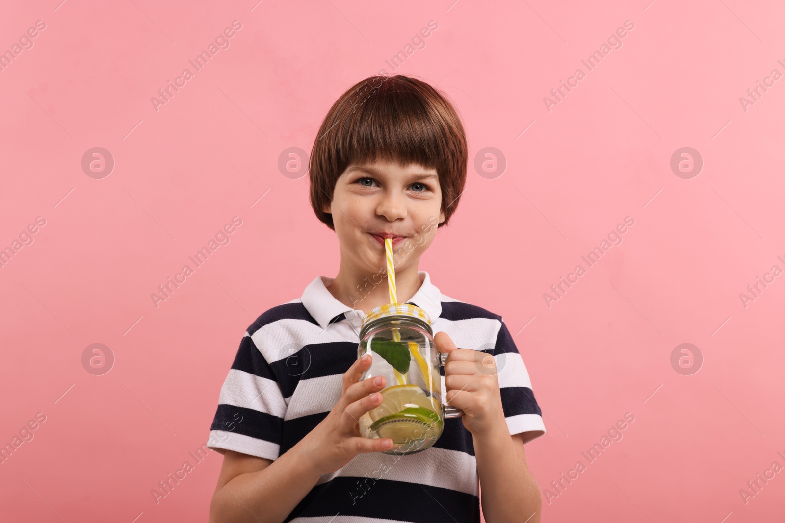 Cute little boy drinking lemonade on pink background. Refreshing drink Photo of Cute little boy drinking lemonade on pink background. Refreshing drink