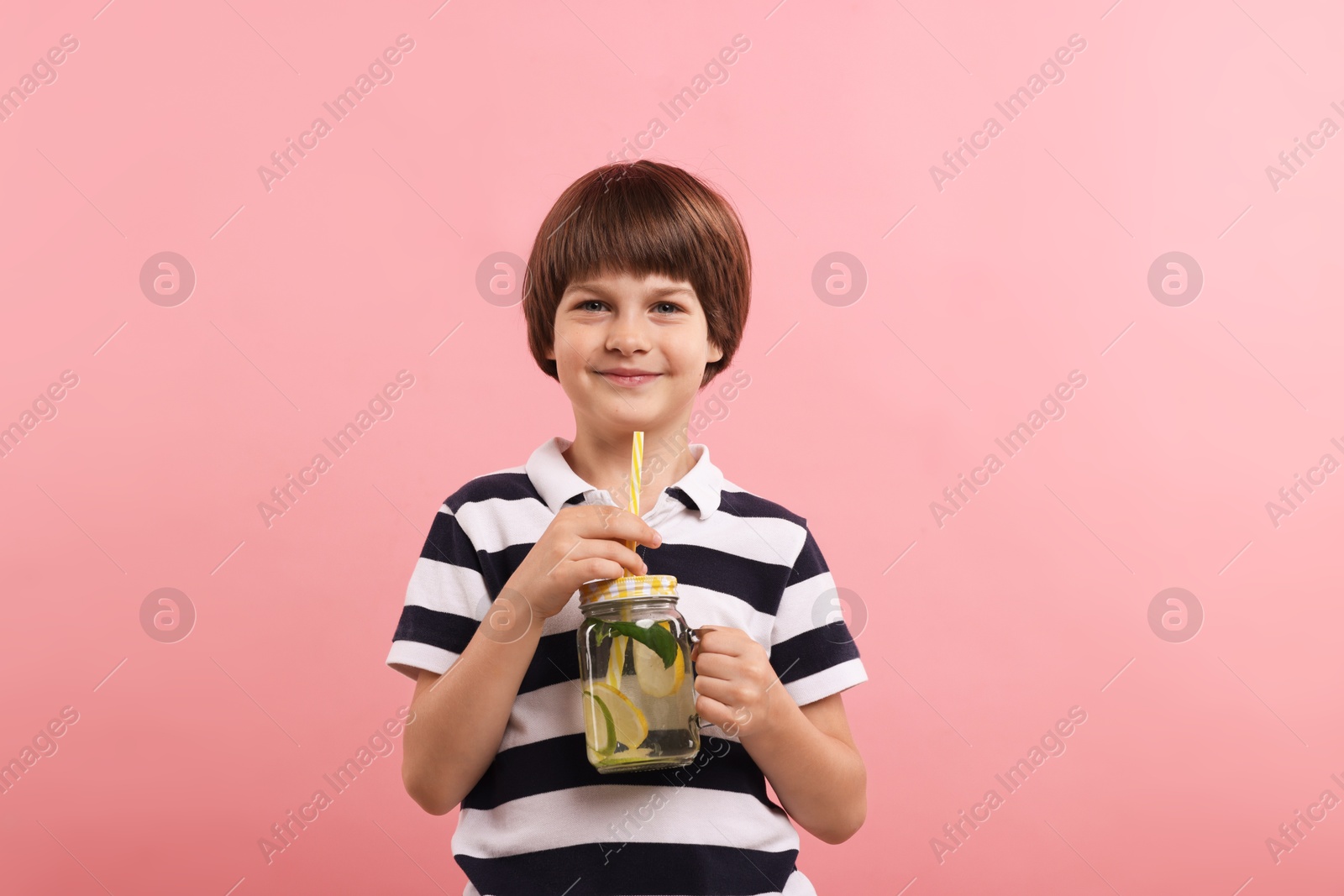 Cute little boy with mason jar of lemonade on pink background. Refreshing drink Photo of Cute little boy with mason jar of lemonade on pink background. Refreshing drink