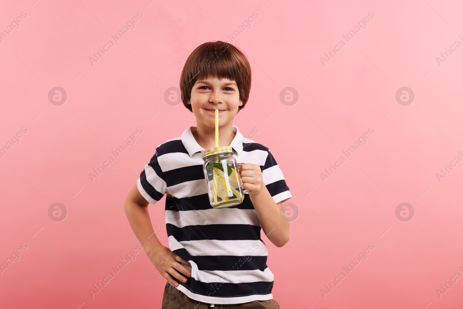 Cute little boy with mason jar of lemonade on pink background. Refreshing drink Photo of Cute little boy with mason jar of lemonade on pink background. Refreshing drink