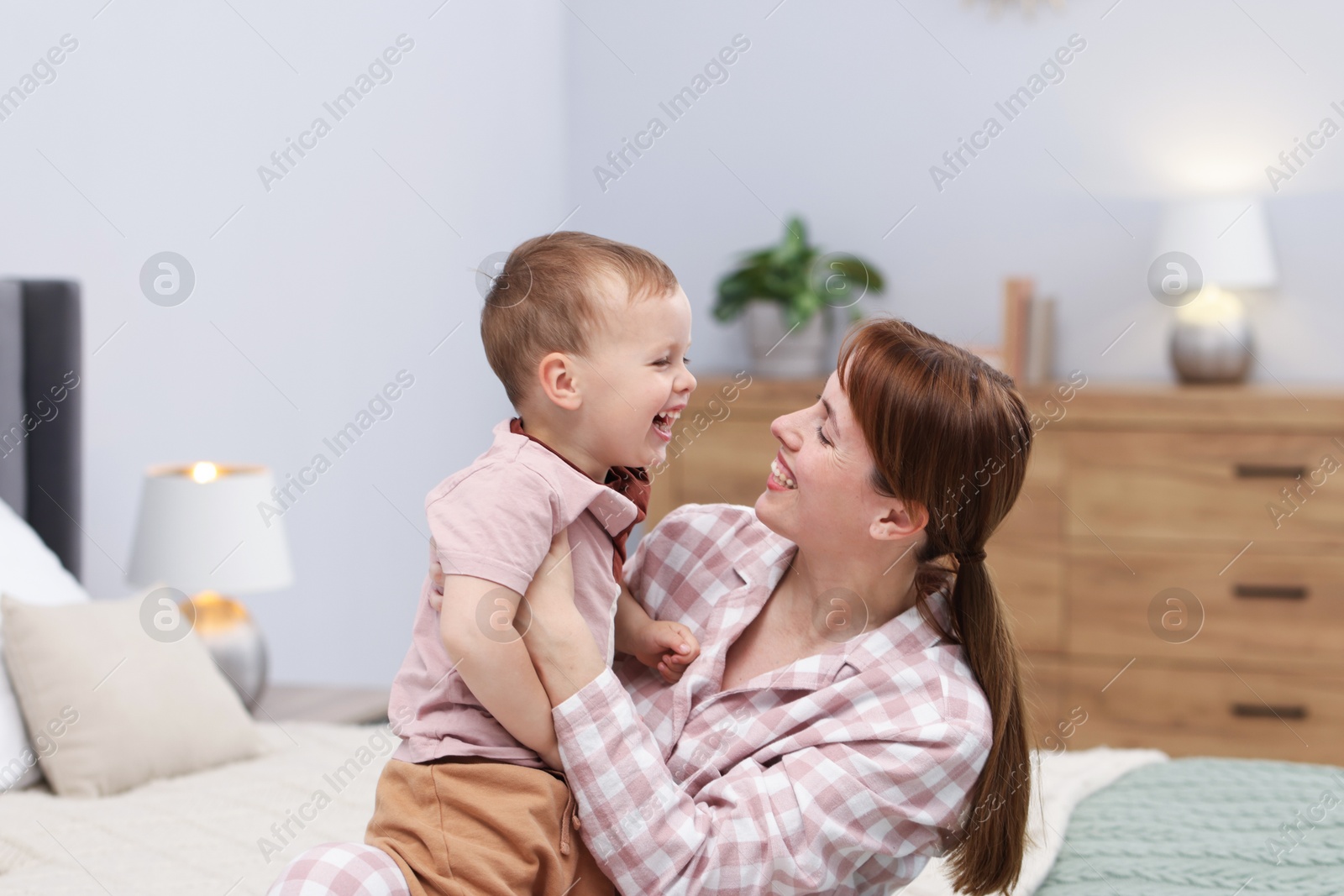 Happy mother with her son on bed at home Photo of Happy mother with her son on bed at home