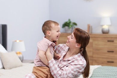 Photo of Happy mother with her son on bed at home