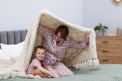 Photo of Happy mother playing with her son on bed at home
