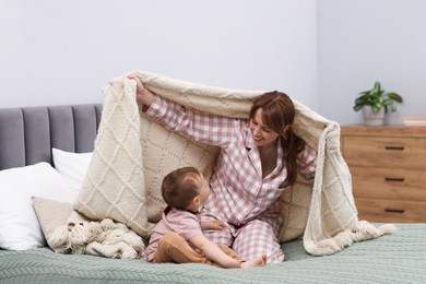 Photo of Happy mother playing with her son on bed at home