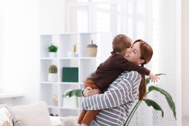 Photo of Happy mother hugging her son at home. Space for text