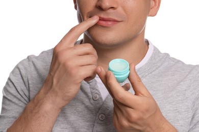 Photo of Young man applying lip balm onto his lips on white background, closeup