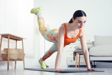 Photo of Young woman in sportswear doing plank exercise at home, low angle view