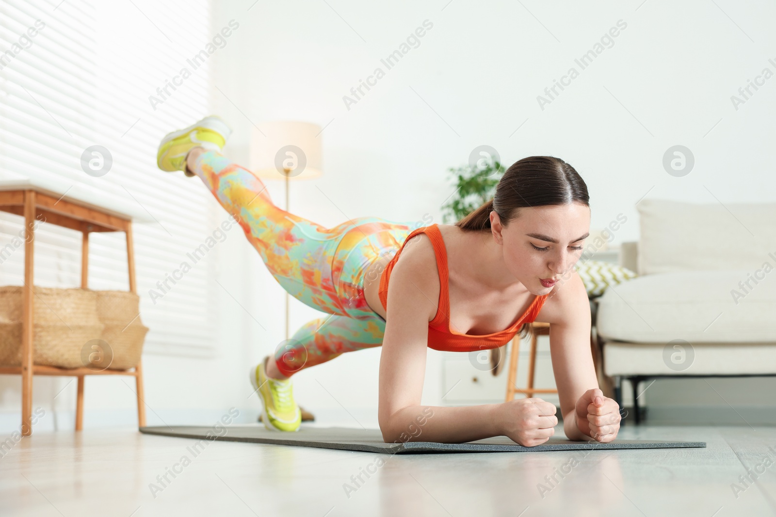 Young woman in sportswear doing plank exercise at home Photo of Young woman in sportswear doing plank exercise at home