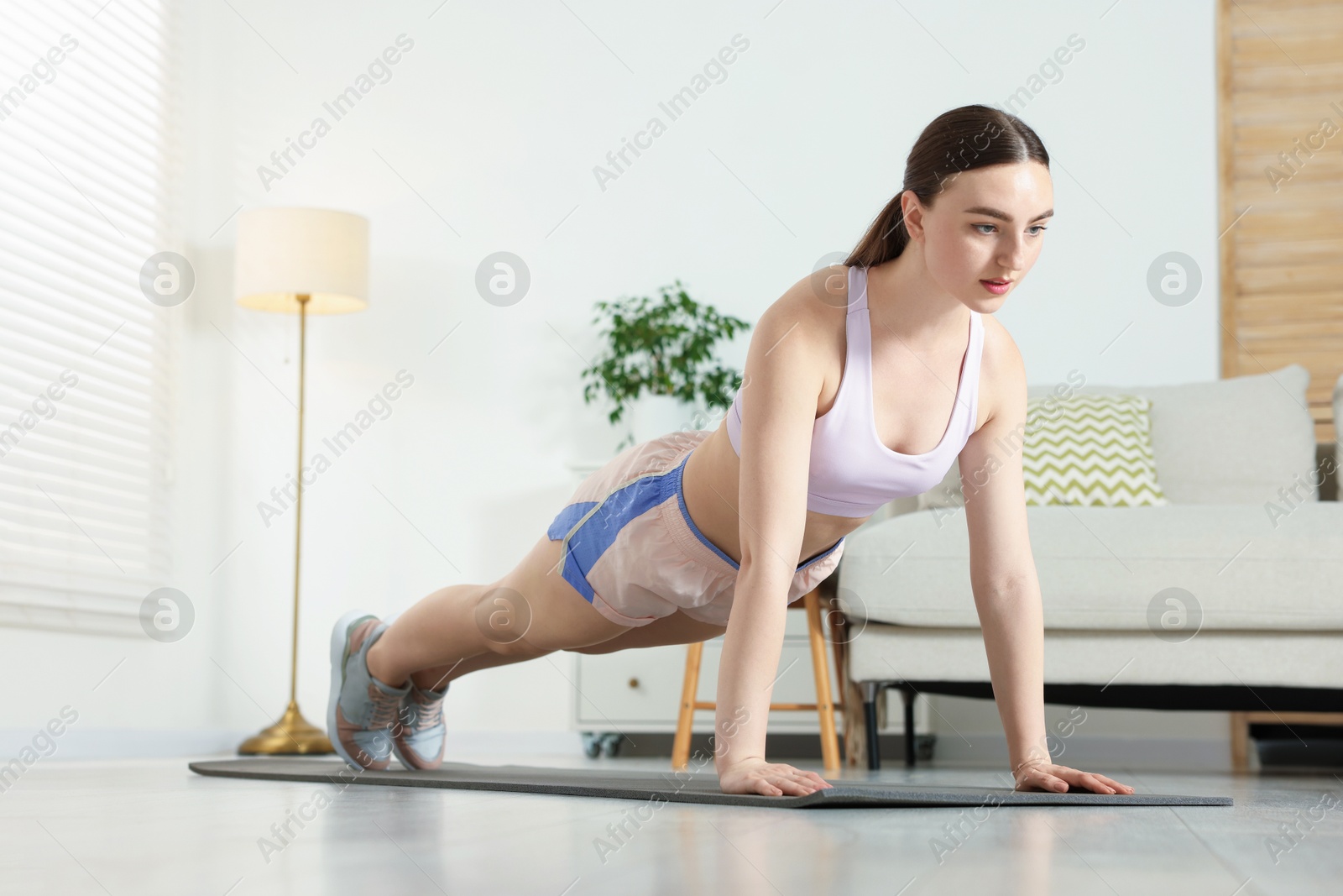 Young woman in sportswear doing plank exercise at home Photo of Young woman in sportswear doing plank exercise at home