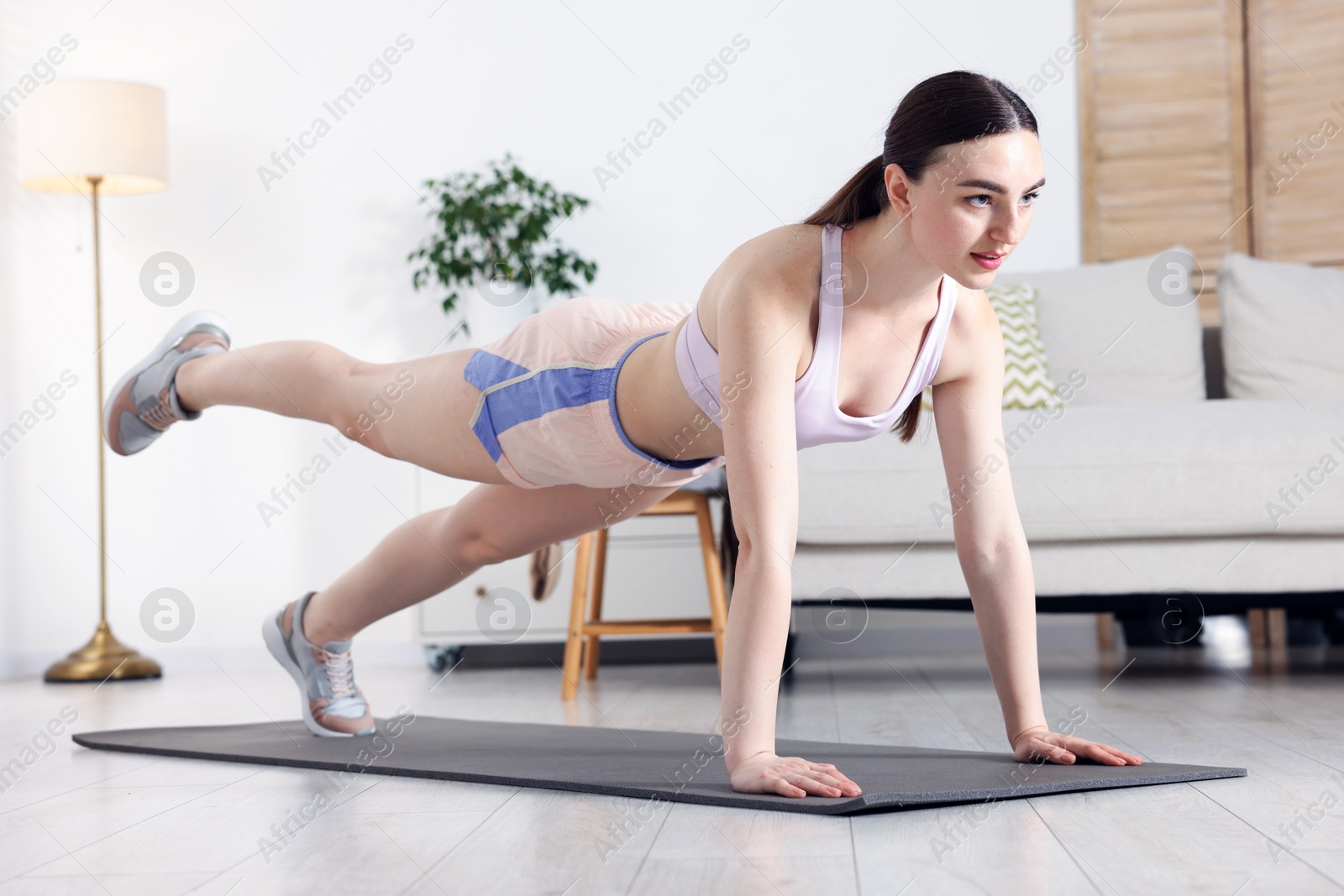 Young woman in sportswear doing plank exercise at home Photo of Young woman in sportswear doing plank exercise at home