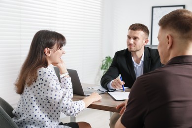 Photo of Couple having meeting with business consultant at table in office