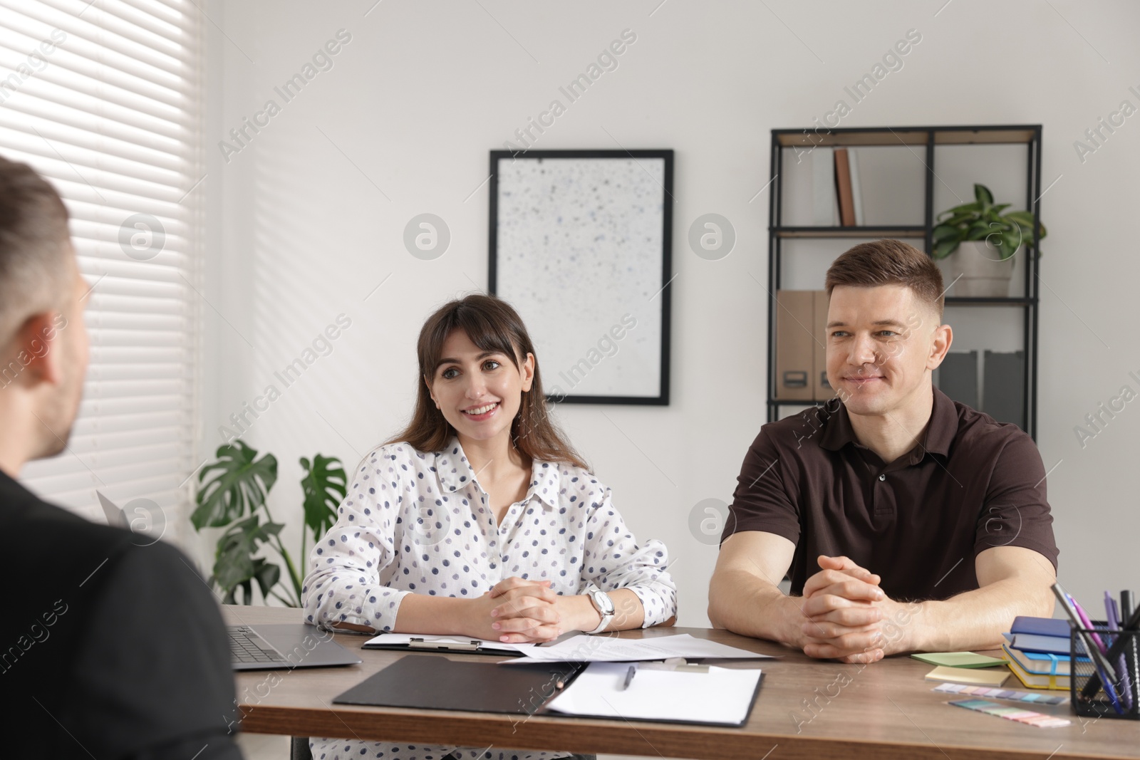 Couple having meeting with business consultant at table in office Photo of Couple having meeting with business consultant at table in office