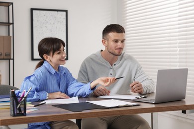 Photo of Consultant working with client at table in office. Business meeting