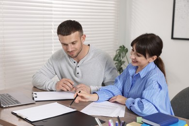 Photo of Consultant working with client at table in office. Business meeting