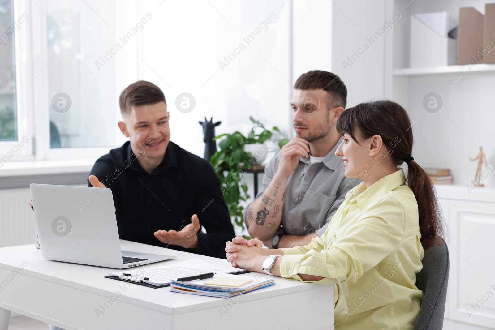 Couple having meeting with business consultant at table in office Photo of Couple having meeting with business consultant at table in office