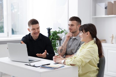 Photo of Couple having meeting with business consultant at table in office