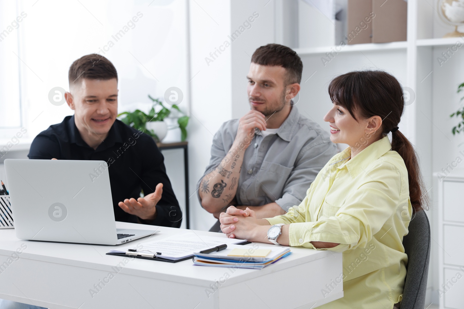 Couple having meeting with business consultant at table in office Photo of Couple having meeting with business consultant at table in office