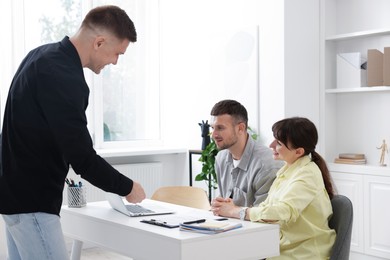 Photo of Couple having meeting with business consultant at table in office