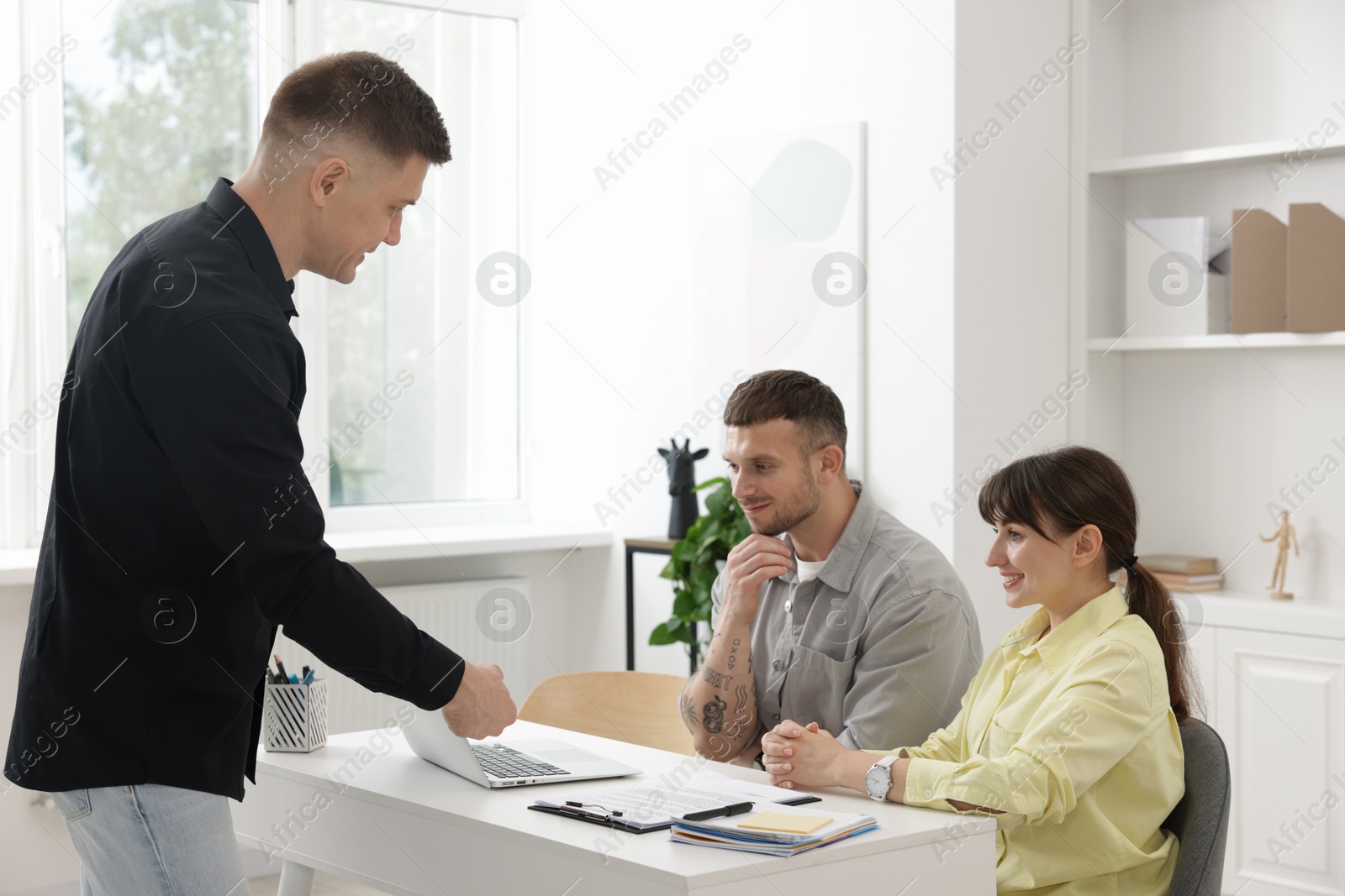 Couple having meeting with business consultant at table in office Photo of Couple having meeting with business consultant at table in office