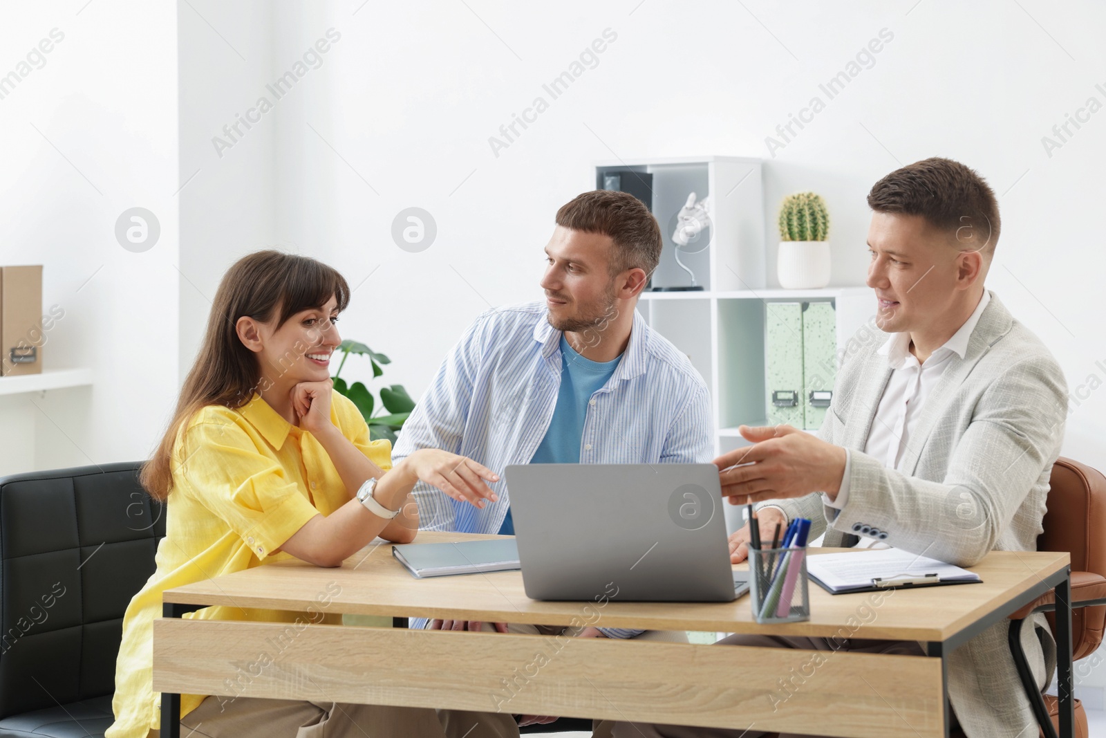 Couple having meeting with business consultant at table in office Photo of Couple having meeting with business consultant at table in office