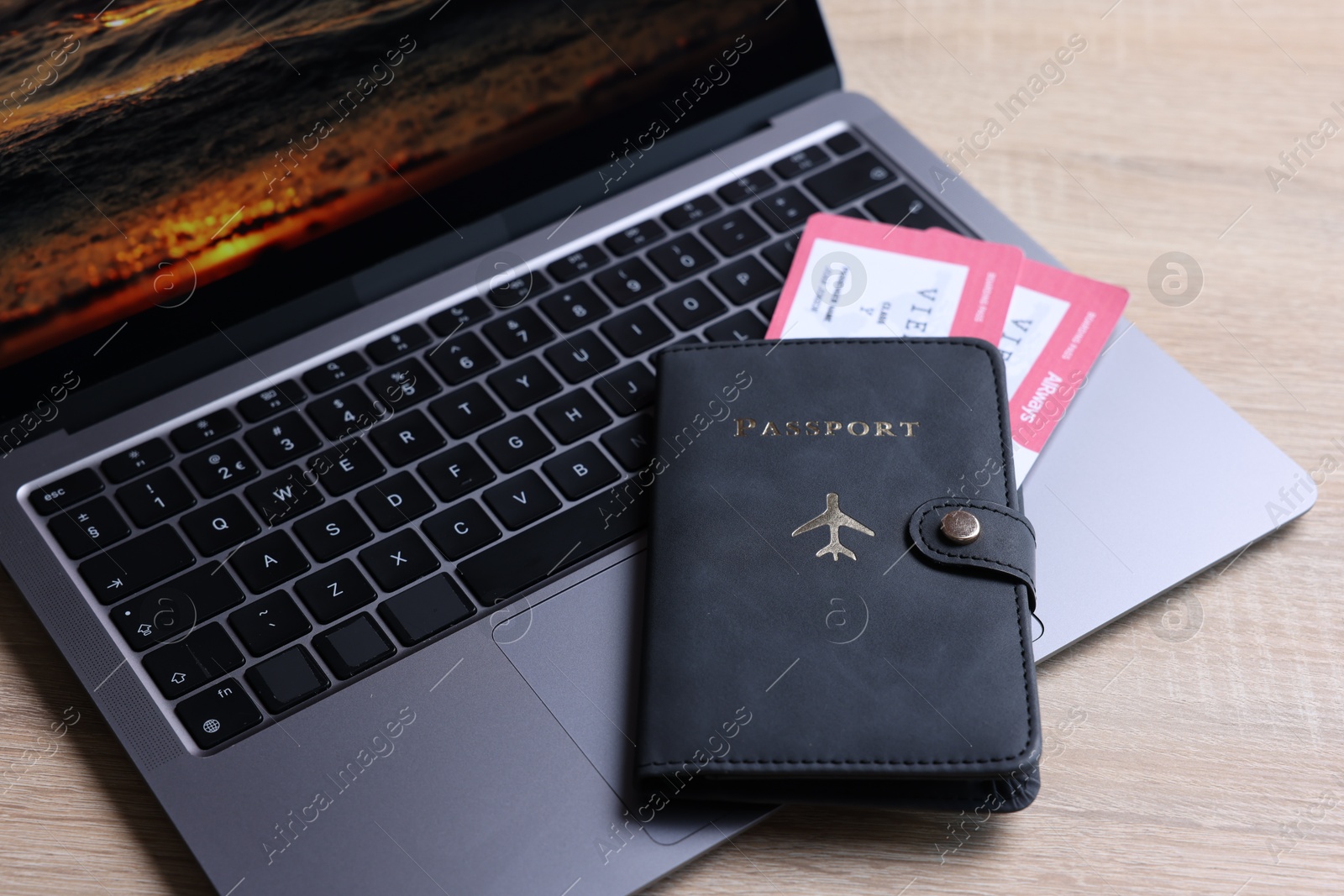 Passport, tickets and laptop on light wooden table, closeup Photo of Passport, tickets and laptop on light wooden table, closeup