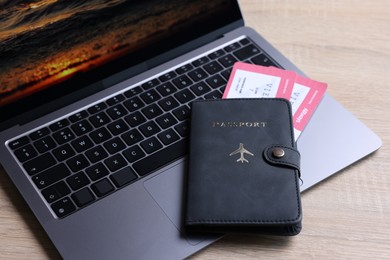 Photo of Passport, tickets and laptop on light wooden table, closeup