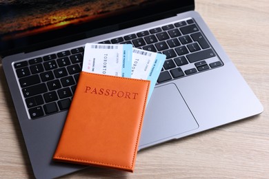 Photo of Passport, tickets and laptop on light wooden table, closeup