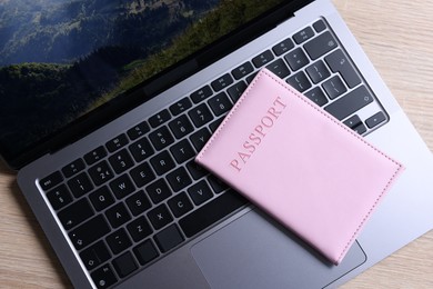 Photo of Passport and laptop on light wooden table, top view