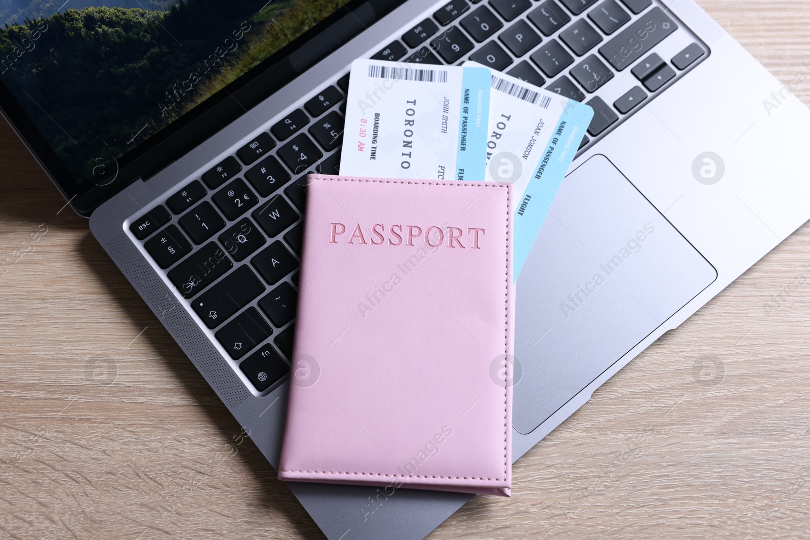 Passport, tickets and laptop on light wooden table, top view Photo of Passport, tickets and laptop on light wooden table, top view