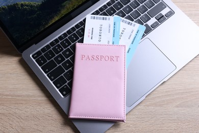 Photo of Passport, tickets and laptop on light wooden table, top view
