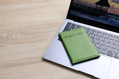 Photo of Passport and laptop on light wooden table, closeup. Space for text