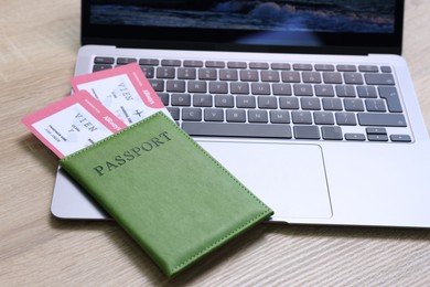 Photo of Passport, tickets and laptop on light wooden table, closeup