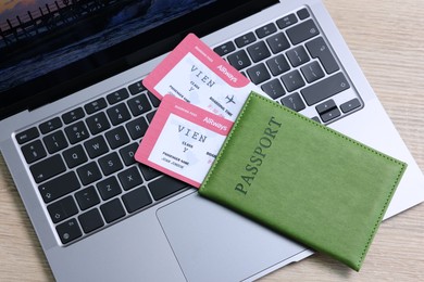 Photo of Passport, tickets and laptop on light wooden table, top view