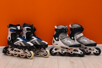 Photo of Pairs of roller skates on floor near orange wall