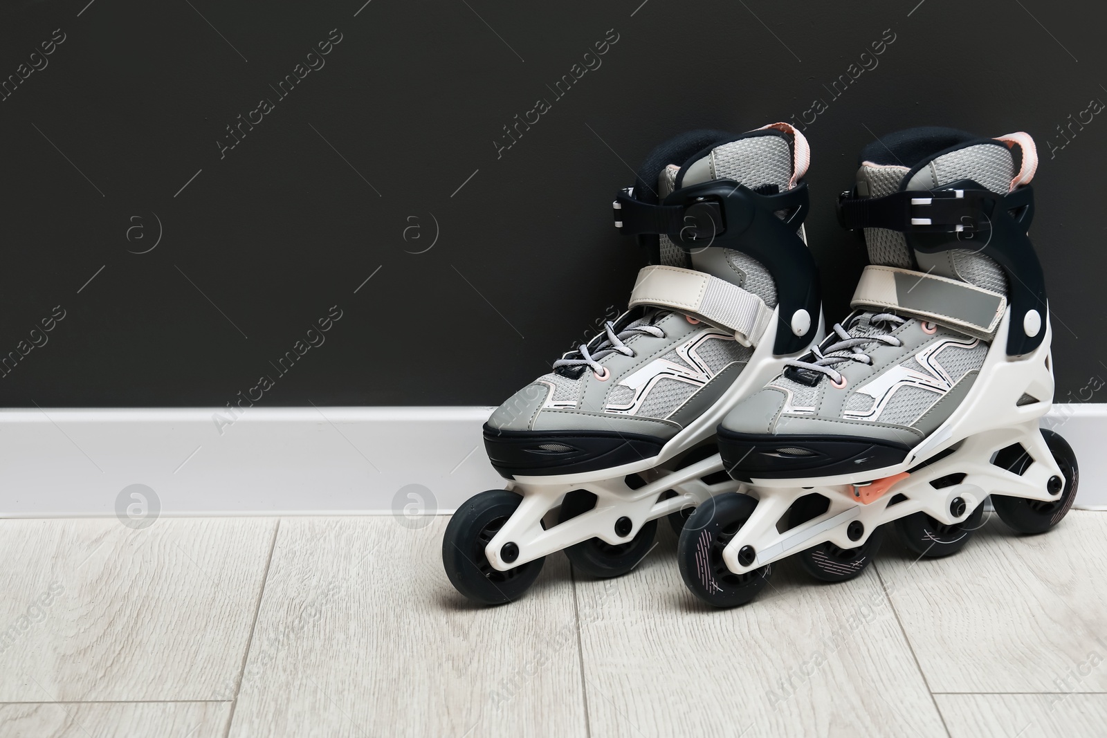 Pair of roller skates on floor near black wall, space for text Photo of Pair of roller skates on floor near black wall, space for text