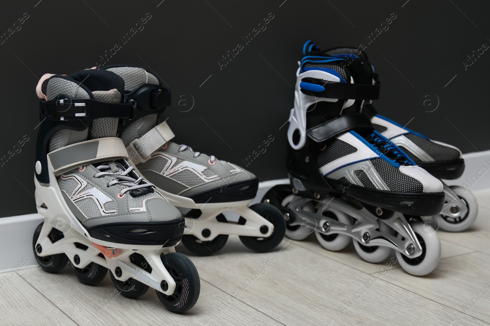 Pairs of roller skates on floor near black wall Photo of Pairs of roller skates on floor near black wall