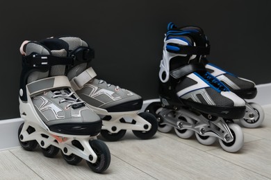 Photo of Pairs of roller skates on floor near black wall
