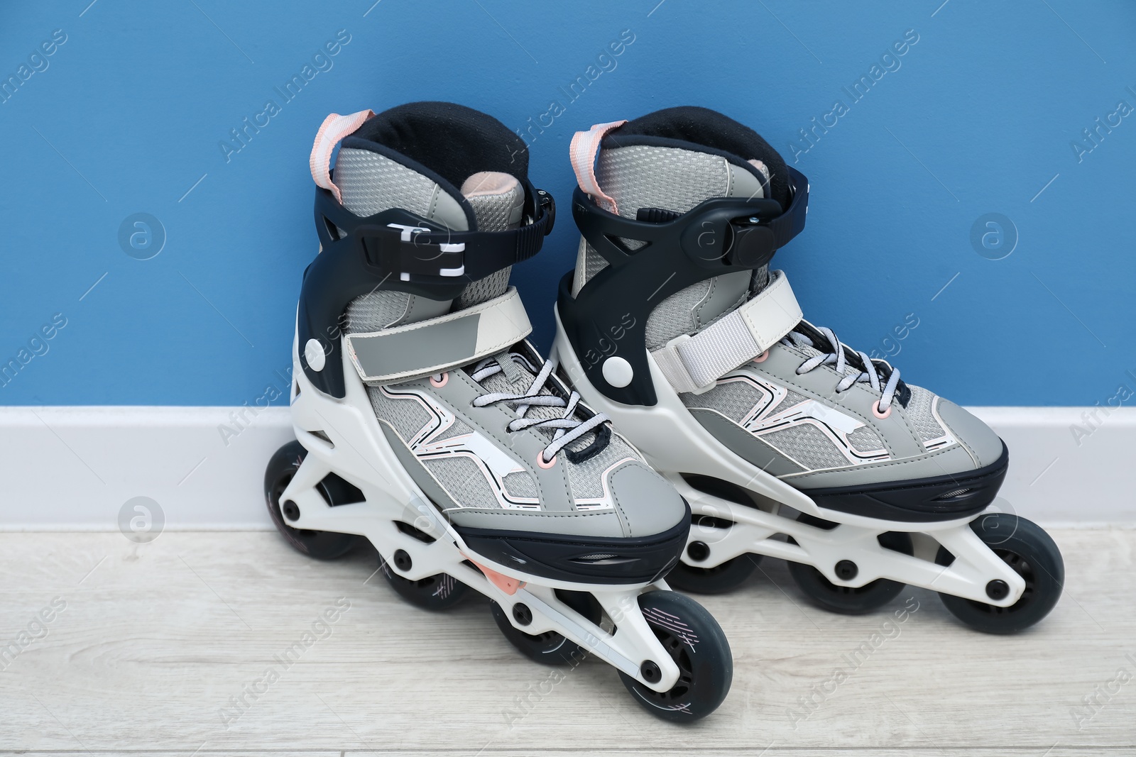 Pair of roller skates on floor near light blue wall Photo of Pair of roller skates on floor near light blue wall