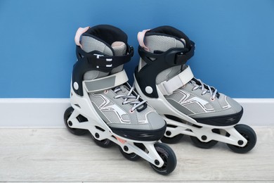 Photo of Pair of roller skates on floor near light blue wall