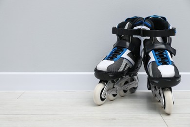 Photo of Pair of roller skates on floor near white wall, space for text