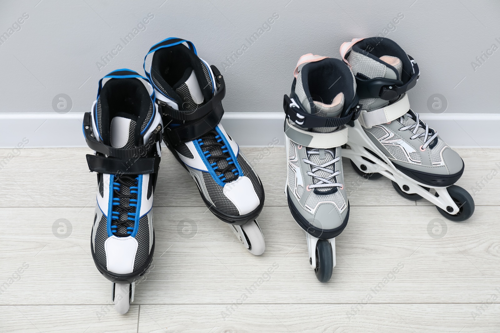 Pairs of roller skates on floor near white wall Photo of Pairs of roller skates on floor near white wall